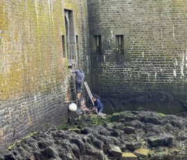 Intervention au pied de la poterne à marée basse Deux bénévoles en intervention dans le port à marée basse au pied de la poterne