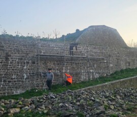 Trois élèves interviennent sur un échafaudage pour la reprise des joints d'un mur de fortification à l'intérieur de l'île du Large